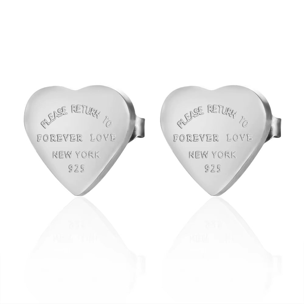 Heart-shaped silver charms with engraved text on a white background
